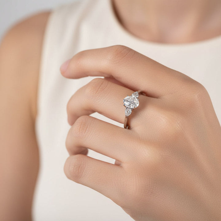 Model wearing 1.5ct oval three-stone moissanite ring in platinum sterling silver.