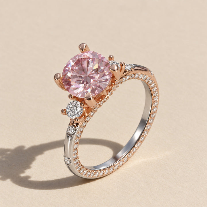 Three-quarter view of pink moissanite ring with white moissanite accents and two-tone sterling silver band
