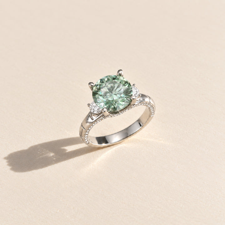 Three-quarter view of 5 carat green moissanite ring with white side stones and pavé sterling silver band
