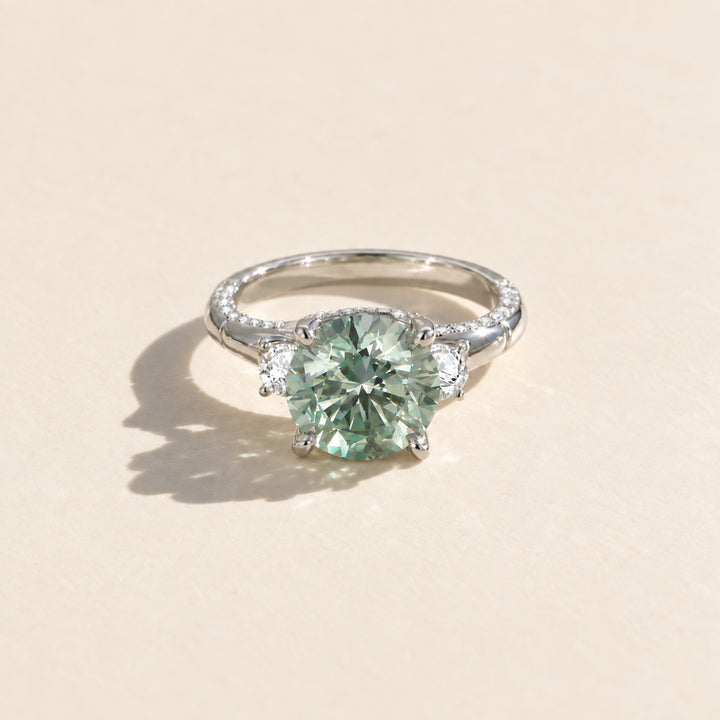 Front view of 5 carat round green moissanite ring with two white side stones
