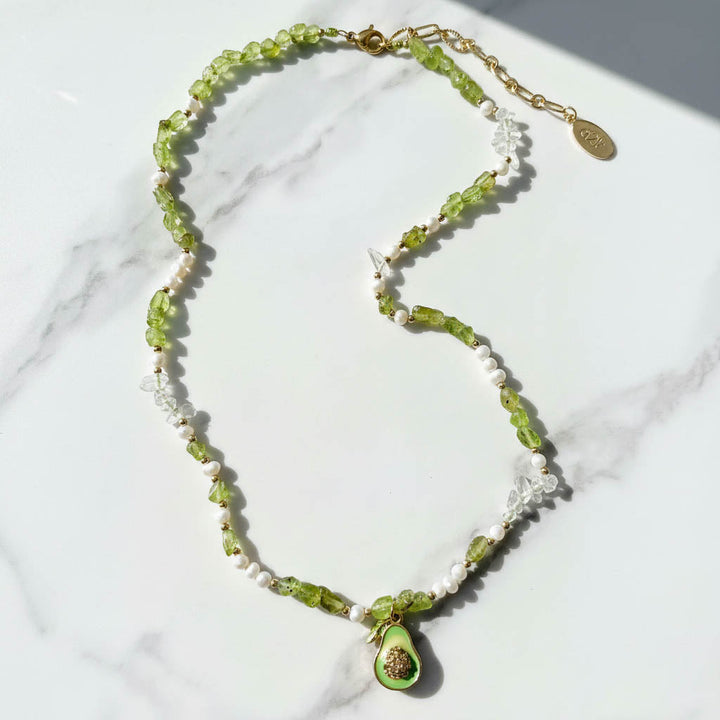 Necklace with green beads and a pendant on a marble surface