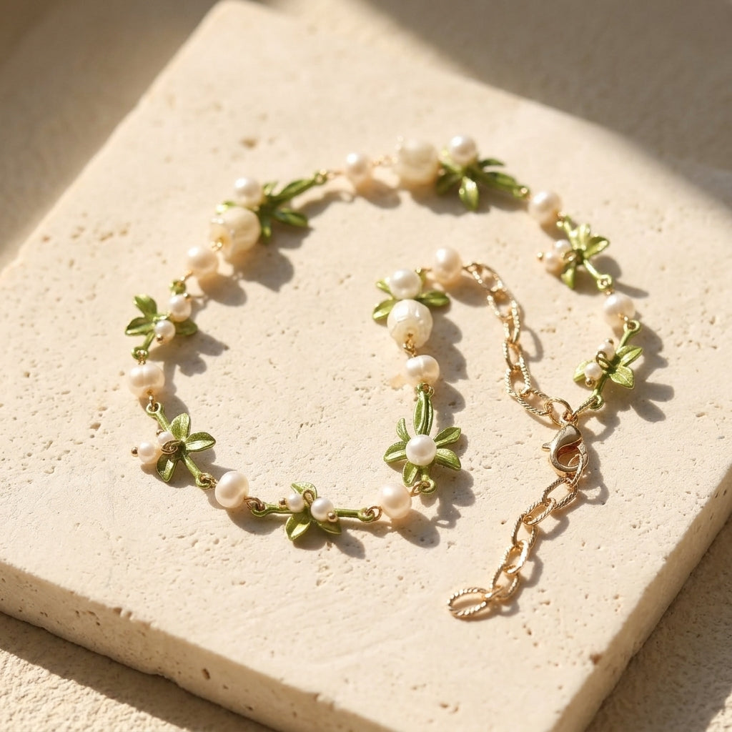 Delicate necklace with green leaves and white pearls on a beige surface