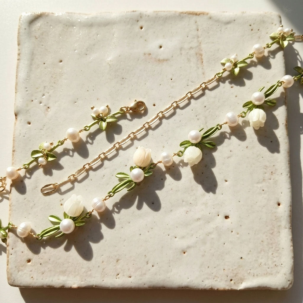 Close-up of lily of the valley necklace with pearl accent on a textured surface
