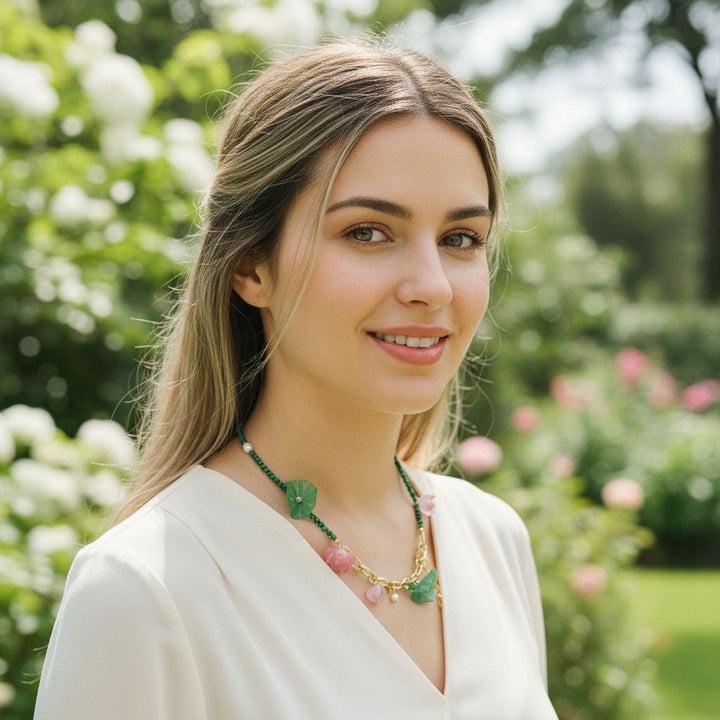 Model wearing green and pink floral necklace in garden setting.