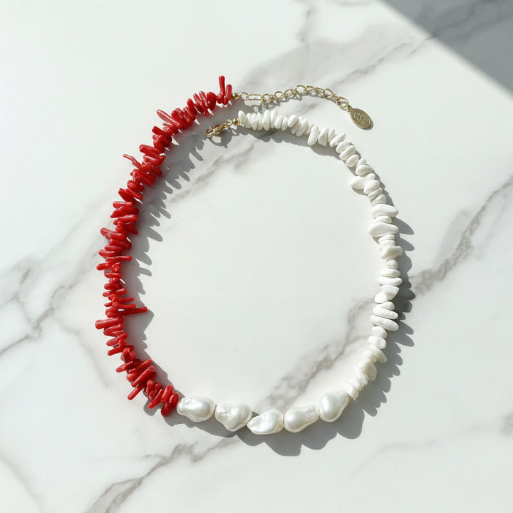 Necklace with red coral and white pearls on a marble surface