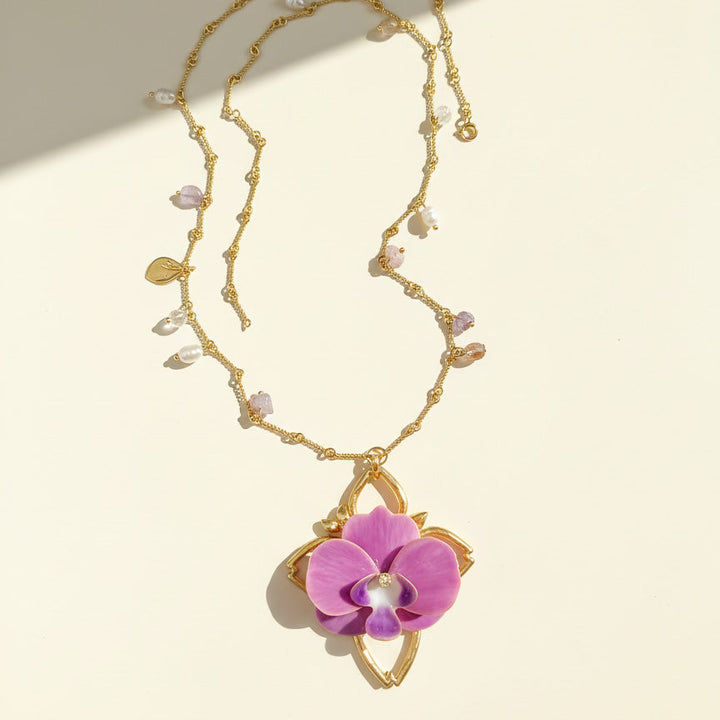 Gold necklace with a pink orchid pendant on a beige background