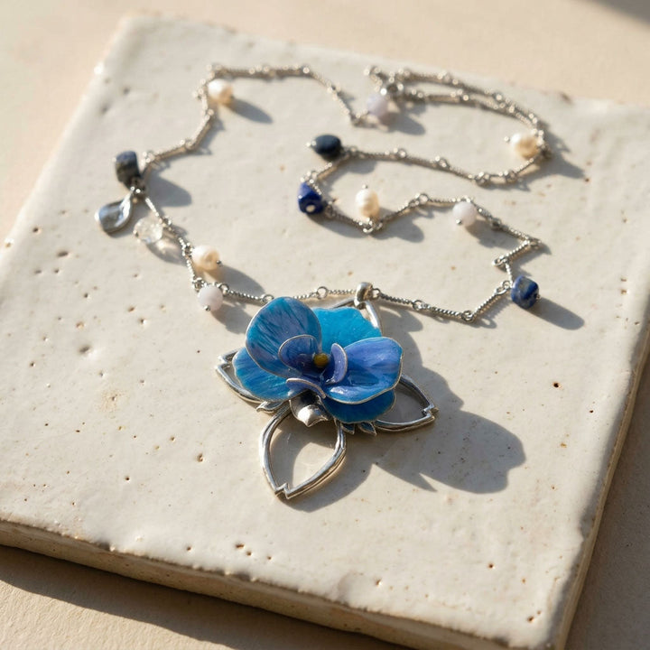 Necklace with a blue forchid pendant on a textured surface