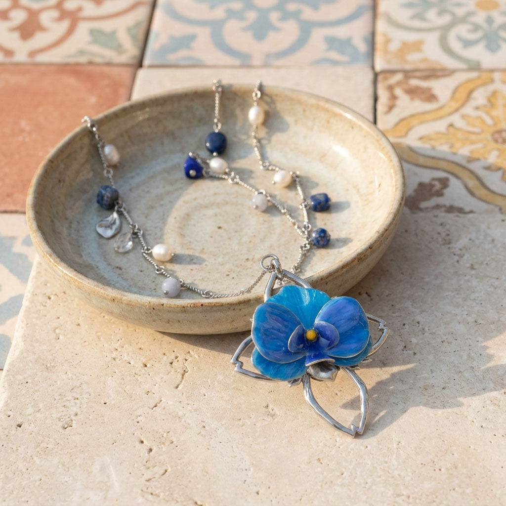 Blue flower necklace on a textured surface with a ceramic dish in the background
