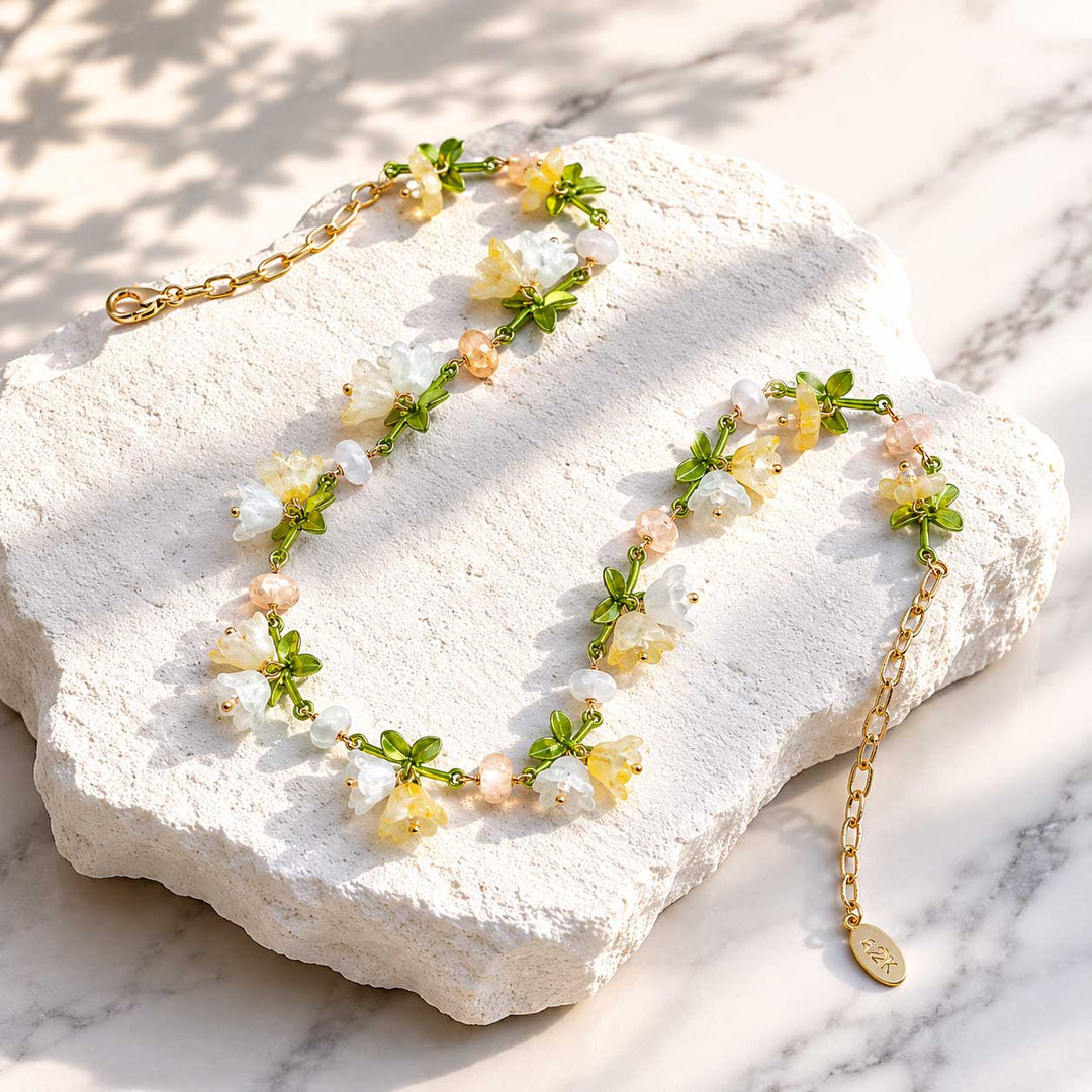 Spring Blossom Garden Necklace with Glass Flowers, Semi-Precious Stones and Enamel Leaves on a white stone surface
