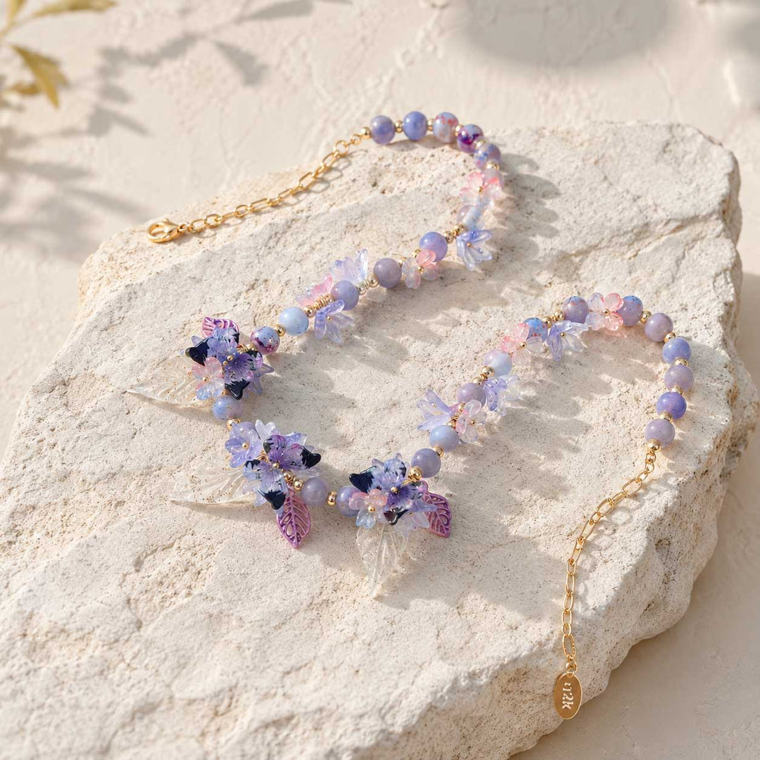 Butterfly Bloom Garden Necklace with Glass Flowers, Resin Butterflies and Hand-Painted Porcelain Beads on a stone surface