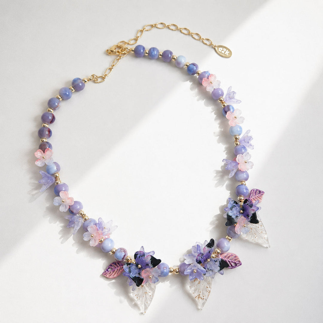 Colorful beaded necklace with floral and butterfly charms on a white background