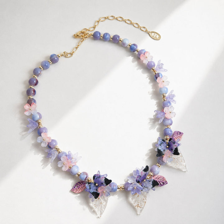 Colorful beaded necklace with floral and butterfly charms on a white background