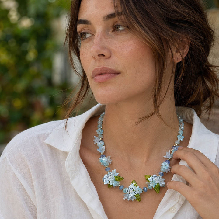 Blue butterfly floral statement necklace worn on model in natural garden setting