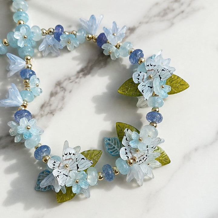Necklace with floral and butterfly designs on a marble surface