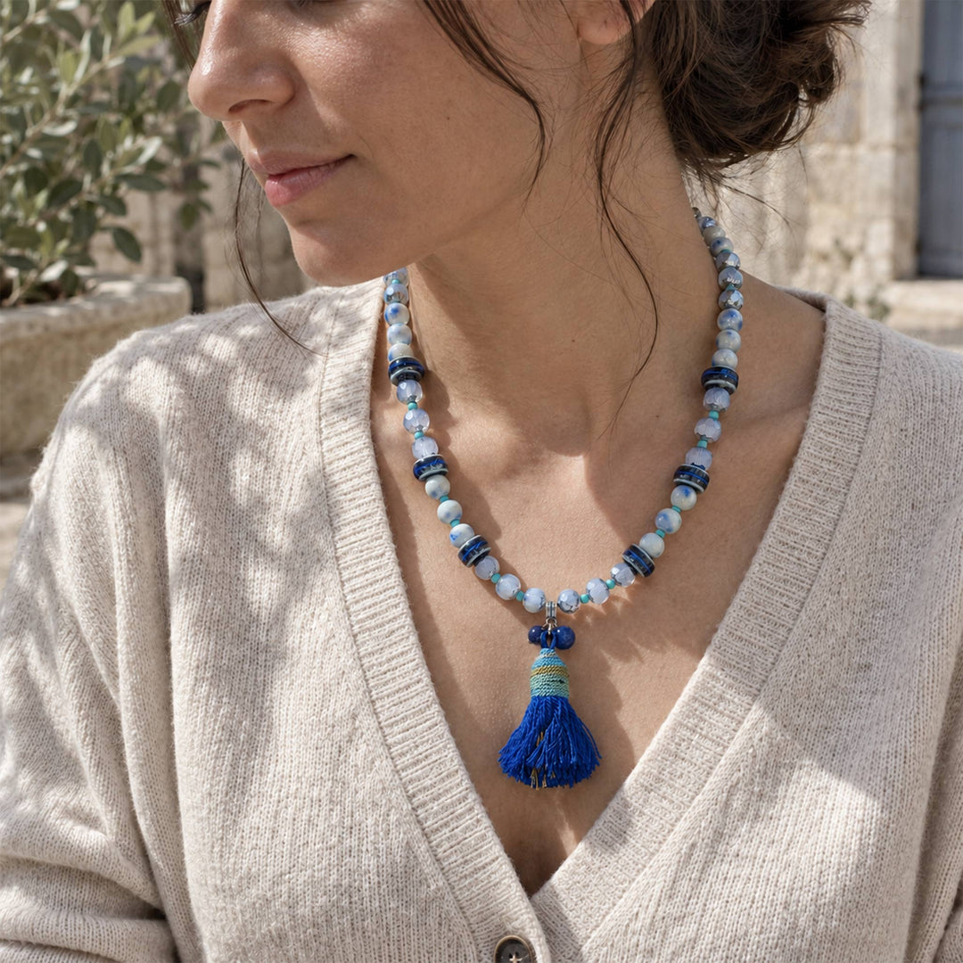 Model wearing a lapis and porcelain tassel necklace with silver-tone details outdoors.