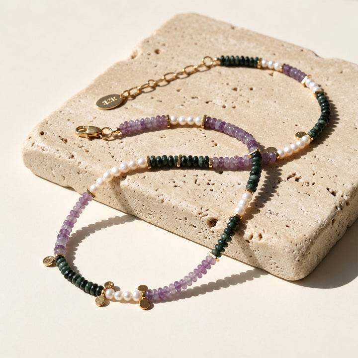 Amethyst, Kambaba Jasper and freshwater pearl necklace with gold accents displayed on limestone in sunlight