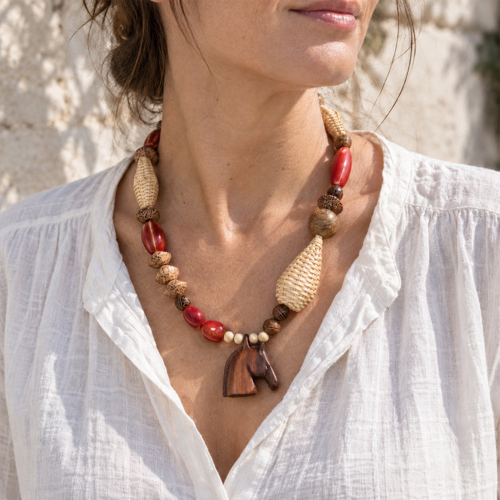 Model wearing a wooden horse pendant necklace with rattan, wooden and porcelain beads.