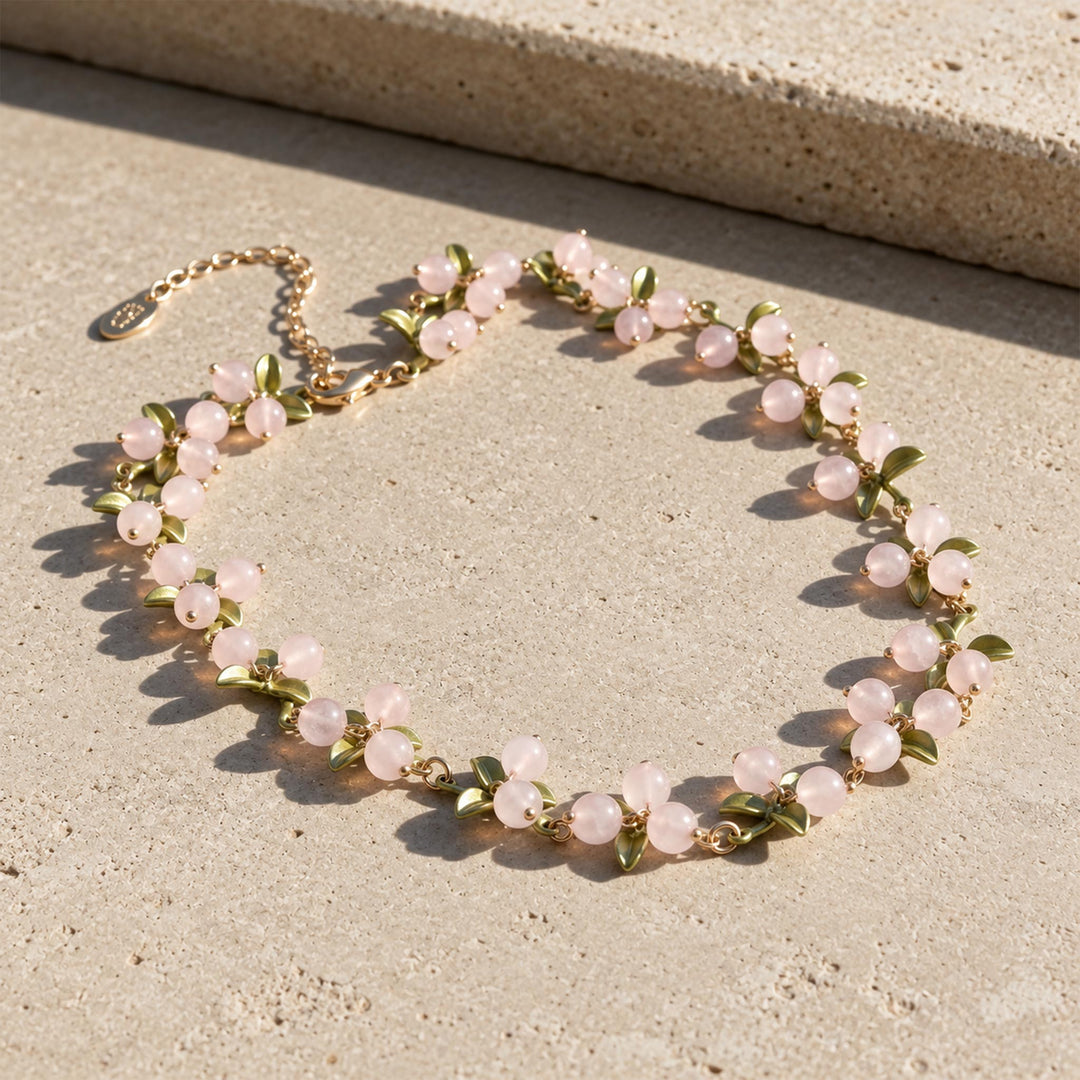 Rose quartz Berry Garden Necklace with green enamel leaves and gold-plated details in sunlight