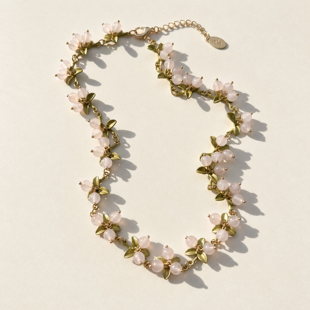 Rose quartz Berry Garden Necklace with green enamel leaves and gold-plated details in sunlight