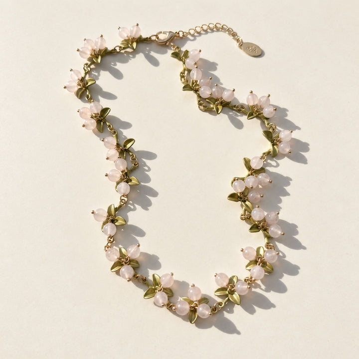 Rose quartz Berry Garden Necklace with green enamel leaves and gold-plated details in sunlight
