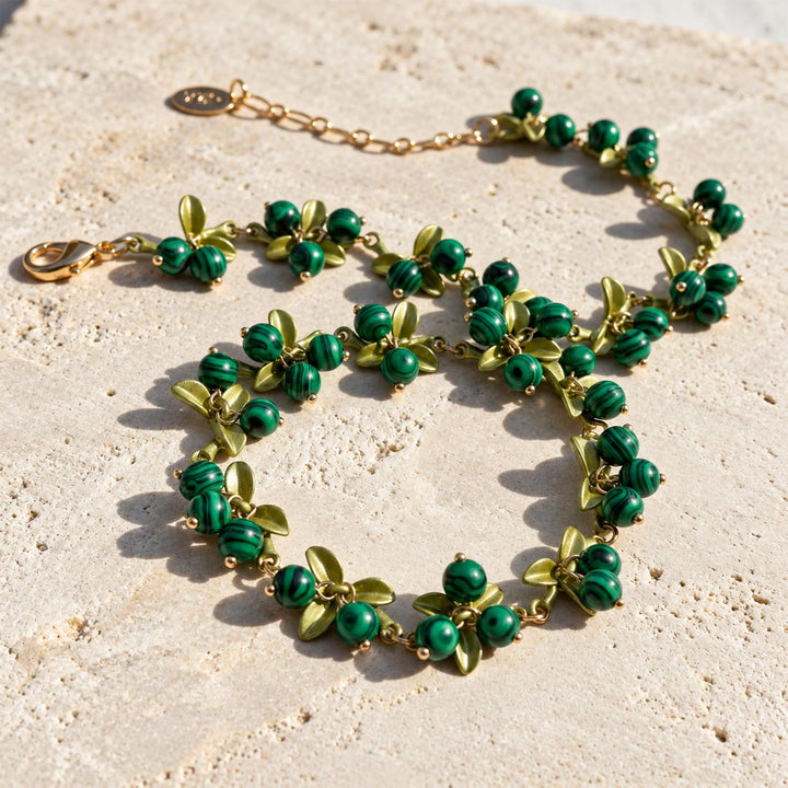 Malachite Berry Garden Necklace arranged on limestone showing green striped stones, enamel leaves and extender chain