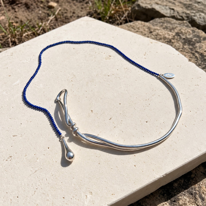 Asymmetric lapis lazuli necklace with curved silver-plated collar and long blue gemstone strand