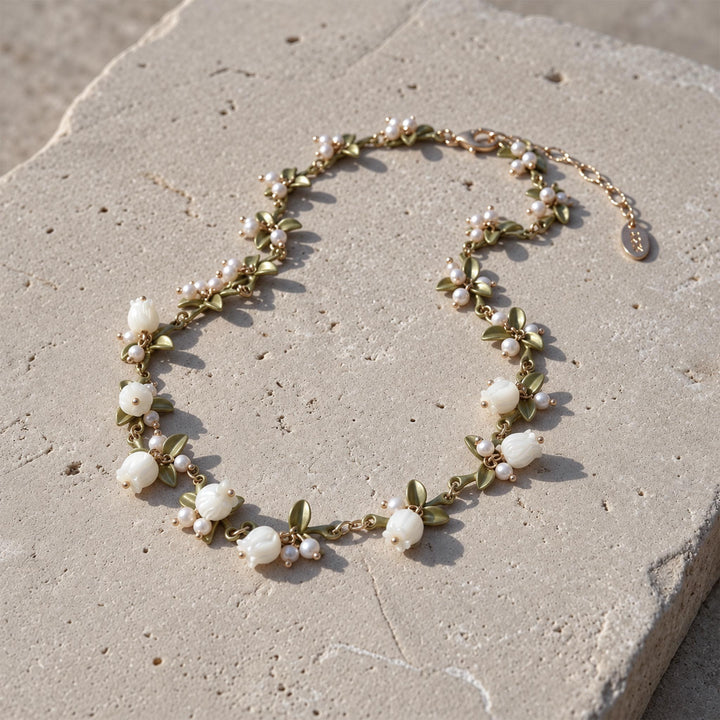 Close-up of a MOP Lily of the Valley necklace with hand-carved mother-of-pearl flowers, freshwater pearls and green enamel leaves.