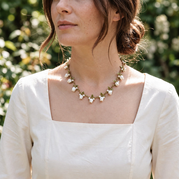 Model wearing a Lily of the Valley mother-of-pearl and freshwater pearl necklace outdoors in natural light.
