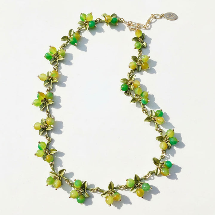 Necklace with green beads and gold chain on a white background