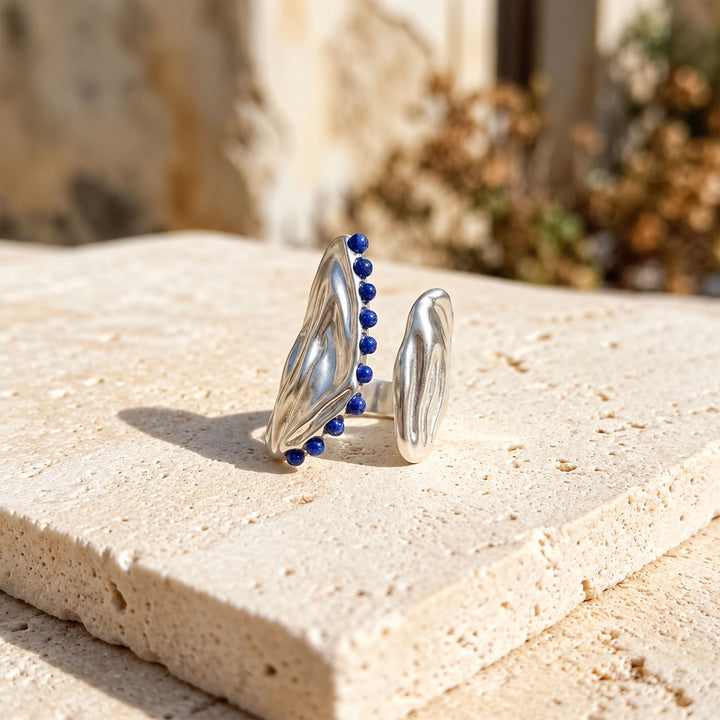 Lapis Lazuli Open Curve Ring with faceted gemstones and polished silver-plated brass on limestone