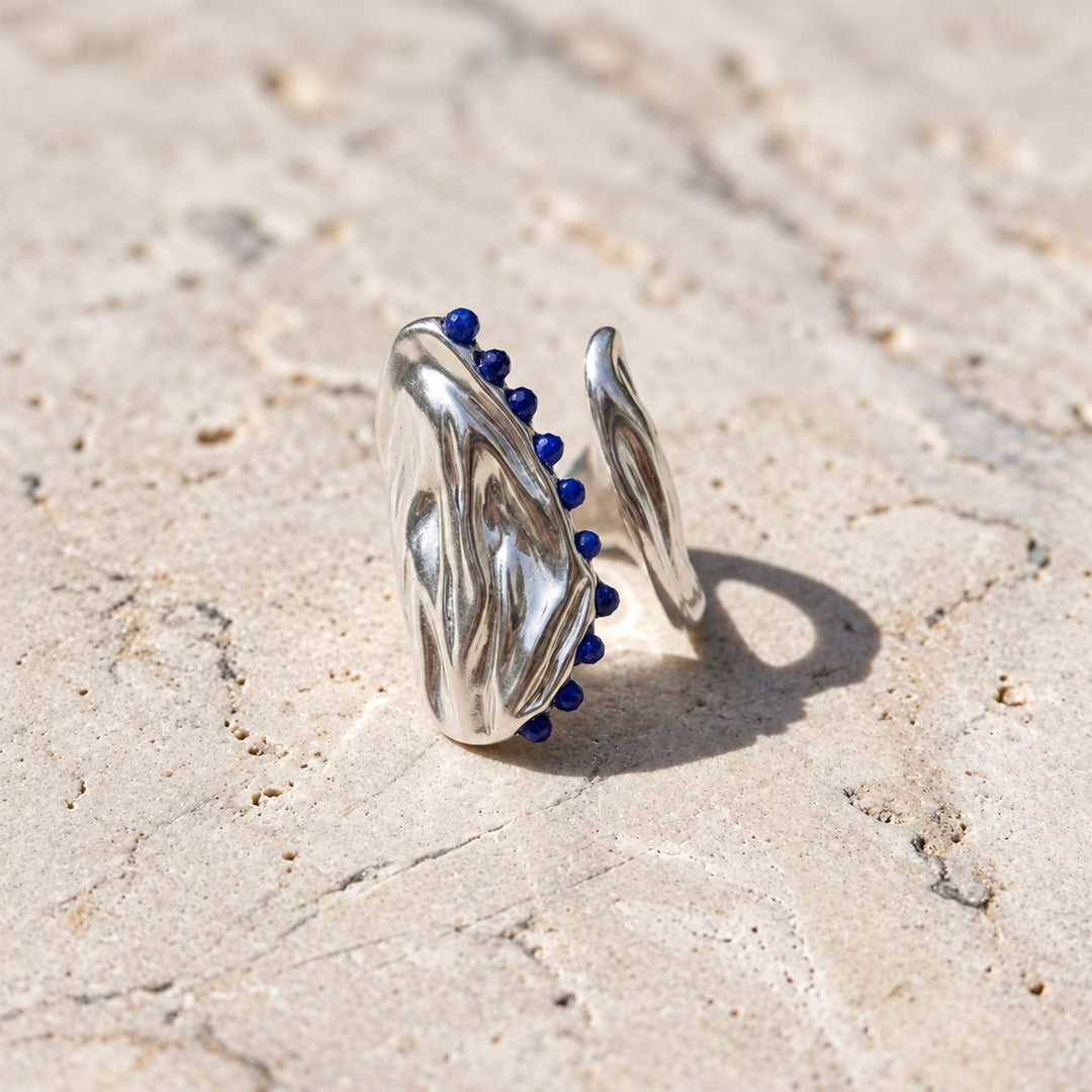 Faceted lapis lazuli gemstones set along an asymmetrical silver-plated open curve ring