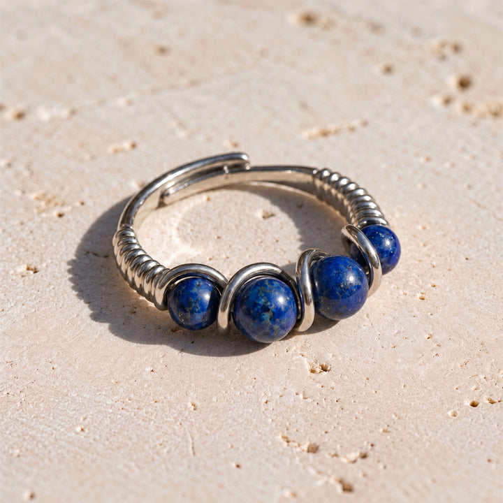 Lapis Lazuli adjustable 925 silver ring with graduated blue gemstones displayed on limestone in sunlight