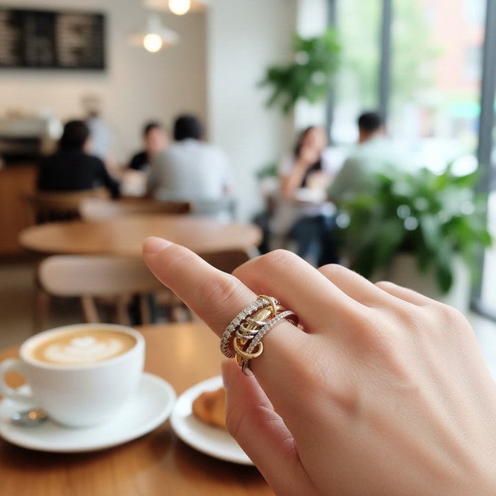 Hand wearing a gold ring with a blurred cafe background