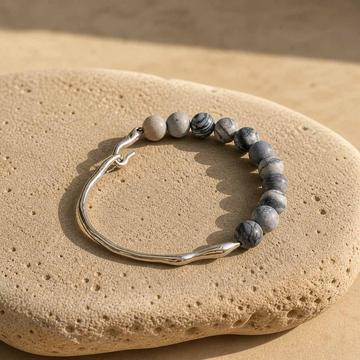Zebra jasper bracelet with stainless steel sculptural hook on natural stone surface