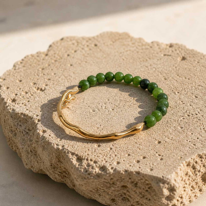 Green chalcedony gemstone bracelet with gold plated hook on textured stone surface