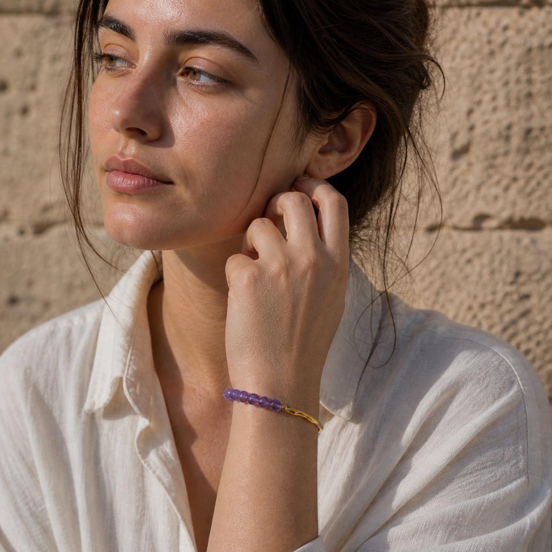 Woman wearing minimalist amethyst gemstone hook bracelet with gold finish