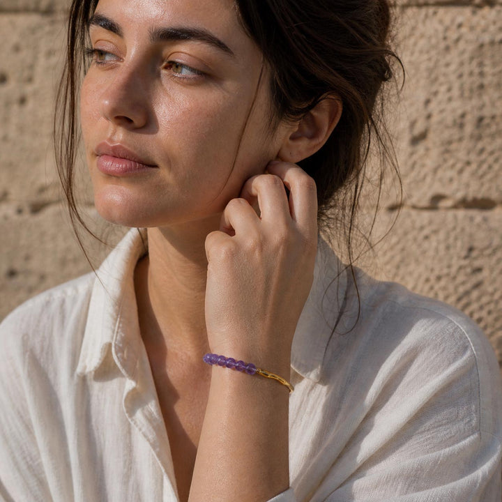 Woman wearing minimalist amethyst gemstone hook bracelet with gold finish