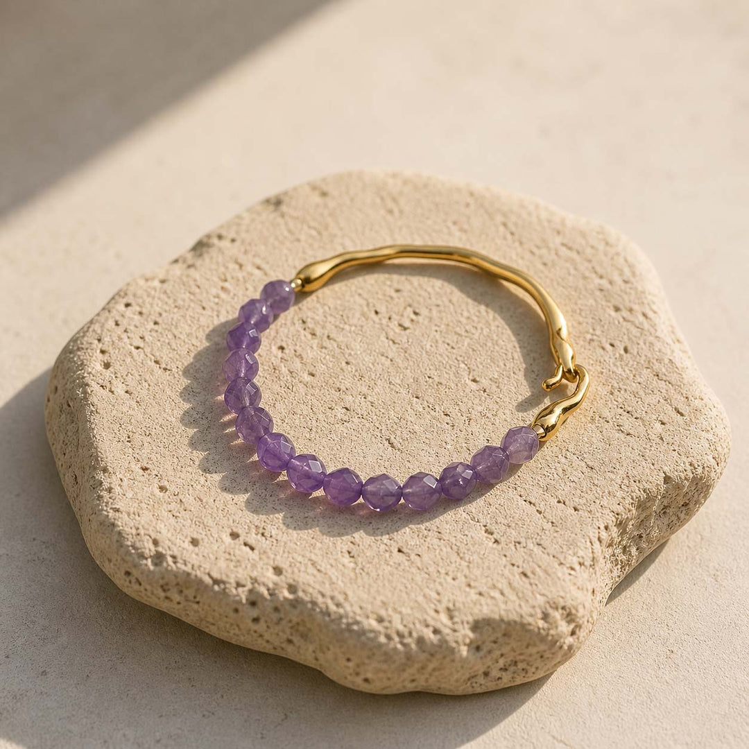 Amethyst and gold hook bracelet styled on natural beige stone slab