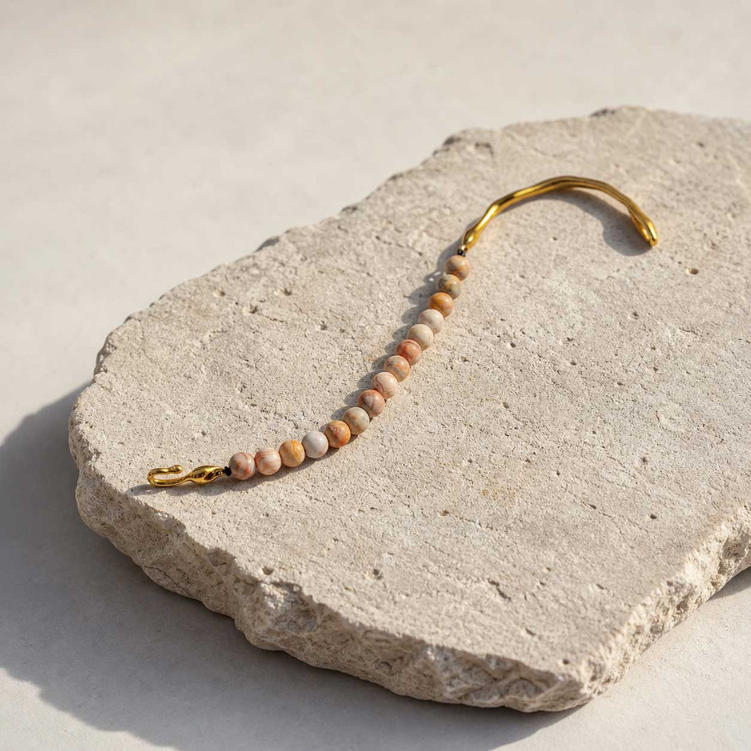 Crazy lace agate beaded bracelet with gold hook clasp on natural stone surface