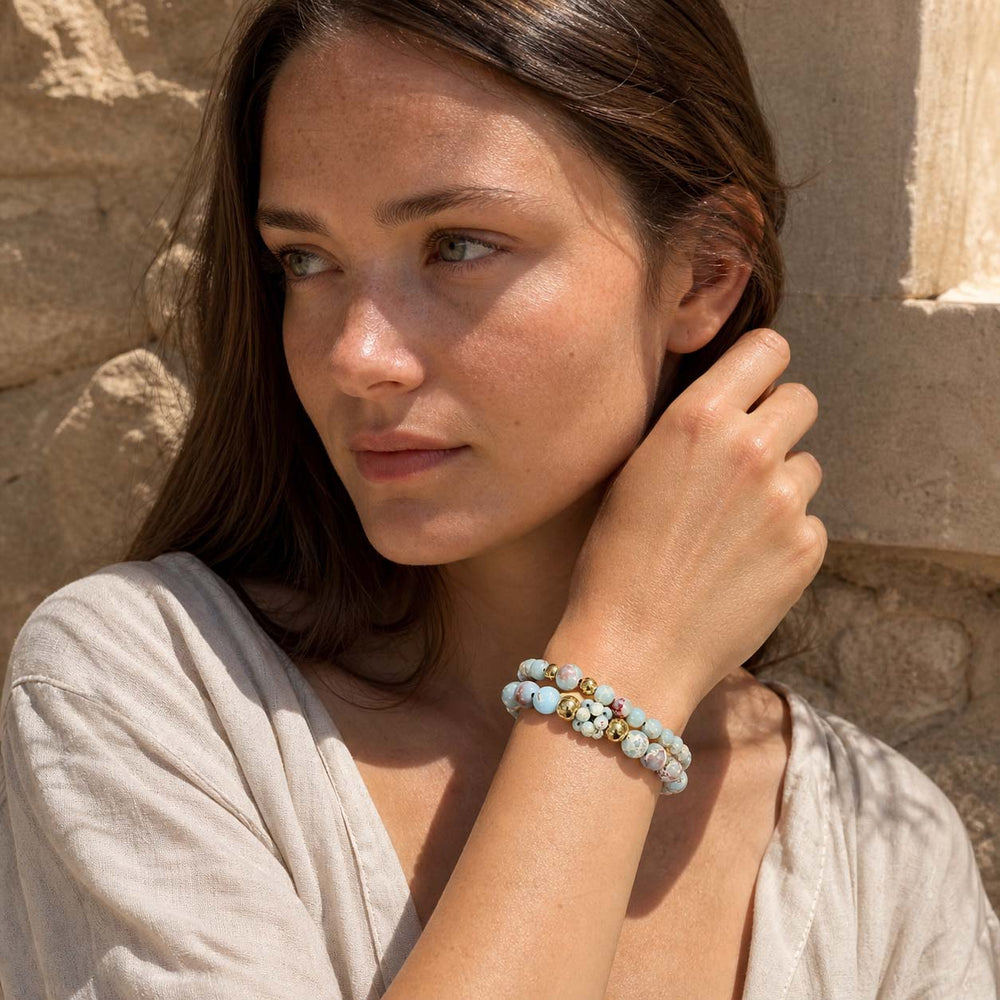 Woman wearing layered Shoushan stone beaded bracelets with gold details