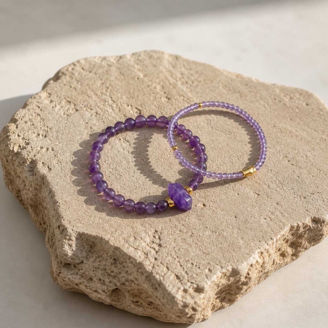Amethyst beaded bracelet set on natural stone surface with gold accents