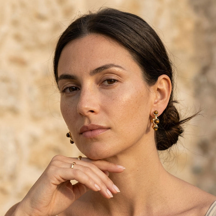 Woman wearing gold earrings with a blurred natural background