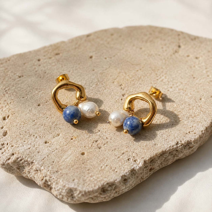 Sodalite and pearl drop earrings on natural stone surface