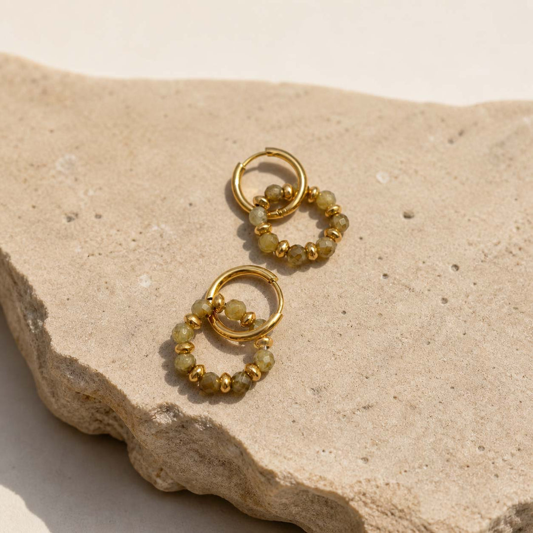 Green gemstone convertible hoop earrings with gold bead charm on natural stone