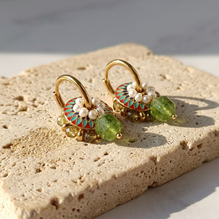Green garnet pearl hoop earrings on textured natural stone