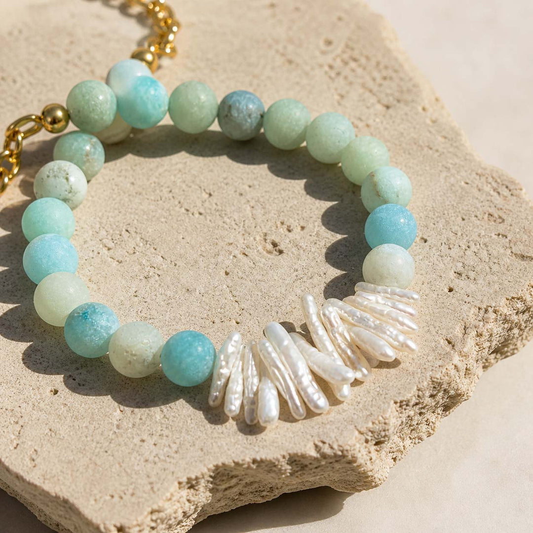 Close-up of baroque pearls and matte amazonite beads on stone surface