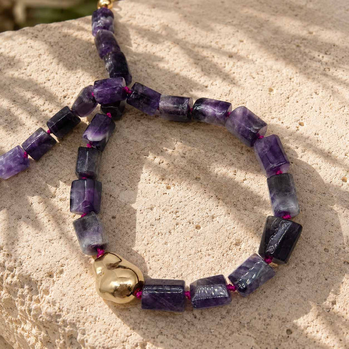 Close-up of natural amethyst gemstone beads and organic 18K gold PVD-coated stainless steel accent on the A2K London amethyst sculptural necklace.