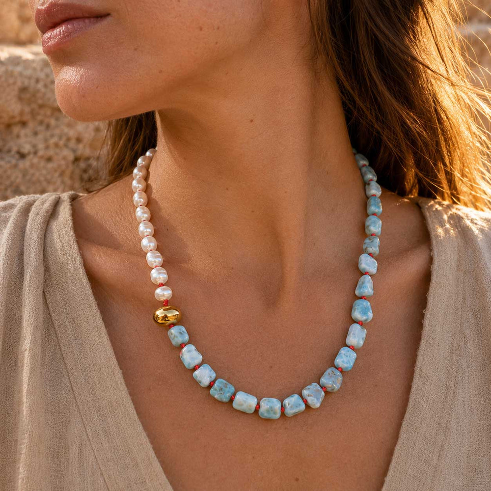 Model wearing Larimar and freshwater pearl necklace in warm natural sunlight